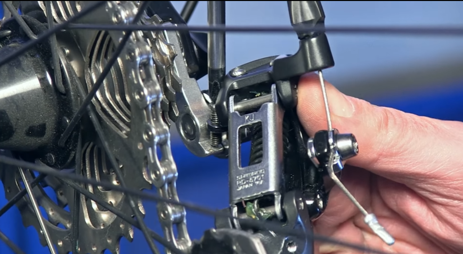 To tighten the chain on a mountain bike with a derailleur locate and tighten the B screw. 