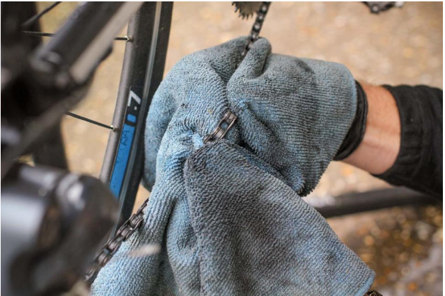 Soak a clean rag in degreaser and hold it over the chain while you rotate the pedal backward so that you coat it thoroughly and rub dirt and grease off it.