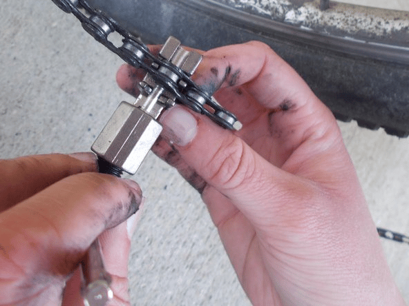 Undo the old chain by breaking it apart with a chain breaker tool.